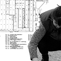 Process image. Scanned image of Anne White crouched placed in front of a floor plan.